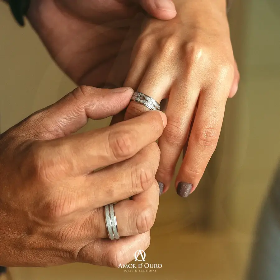 Momento do casal colocando o anel de compromisso prateado no dedo
