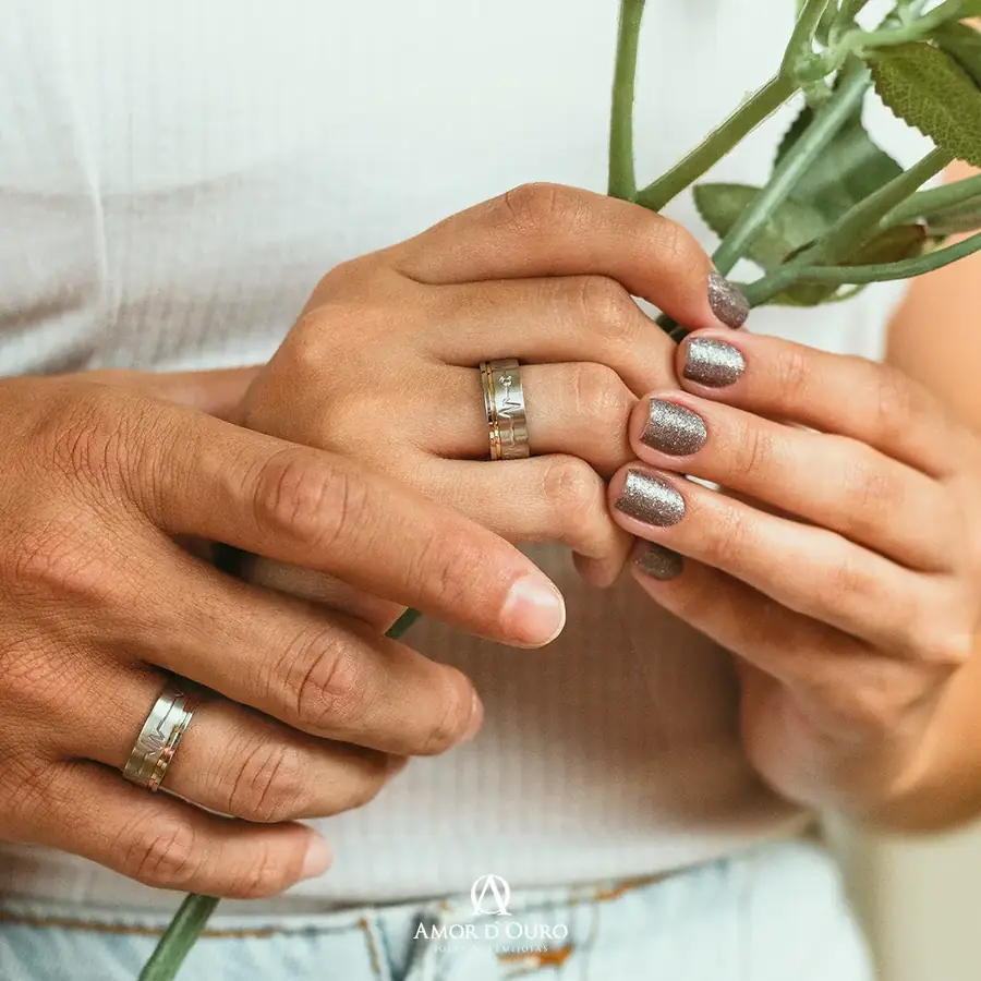 Mãos de um casal com alianças de ouro discretas